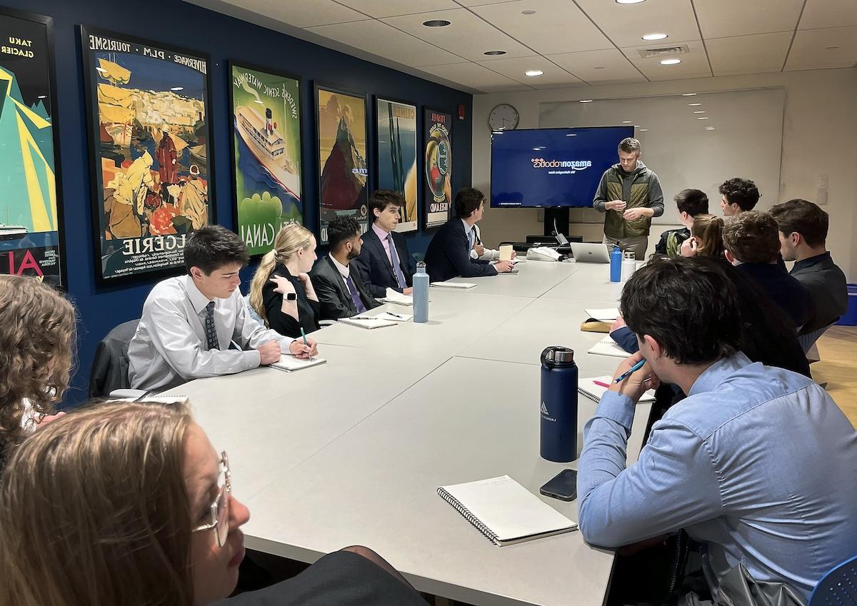 College students dressed in business attire listening to the professor while seated around a table